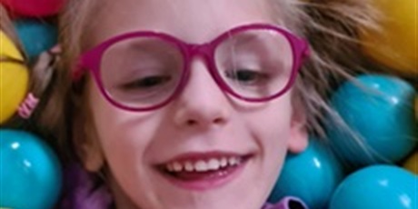 Powiększ grafikę: Dziewczynka w okularach wokół kolorowe piłeczki