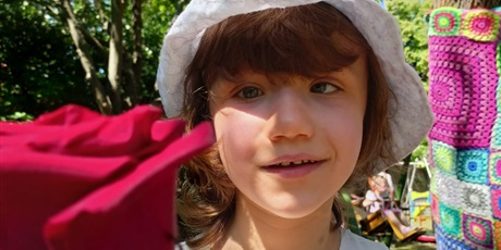 Powiększ grafikę: Dziewczynka w białym kapeluszu trzyma czerwoną różę