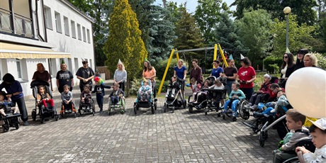 Powiększ grafikę: Dzieci na wózkach stoją na placu przy przedszkolu