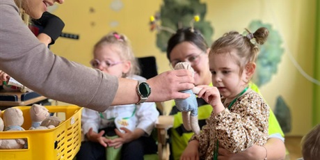 Powiększ grafikę: Dziewczynka sięga ręką po pluszowego misia