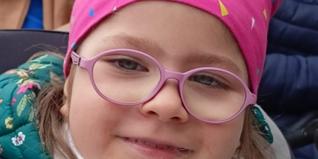 Powiększ grafikę: Uśmiechnięta dziewczynka w okularach patrzy w obiektyw