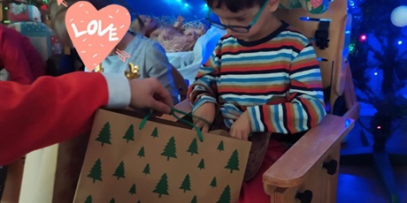 Powiększ grafikę: chłopiec odbiera duży prezent od Mikołaja